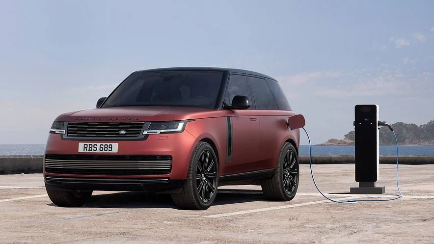2027 Range Rover Electric charging at a public charging station with matte red exterior finish