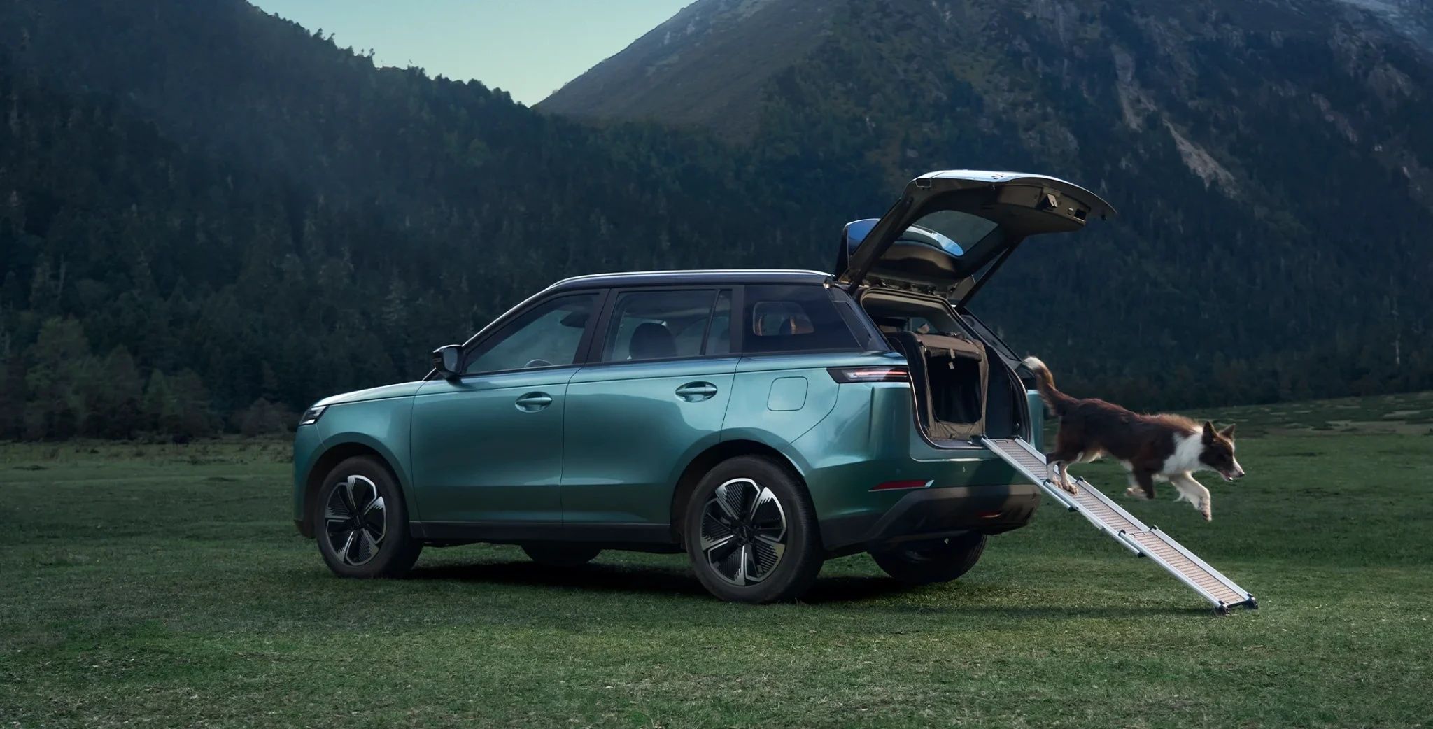 Jaecoo J5 SUV with an open tailgate and pet ramp in a scenic mountain landscape.