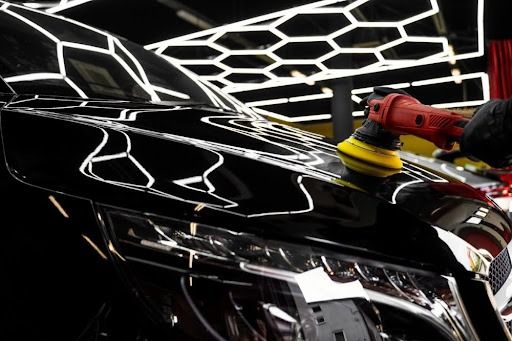 Mechanic polishing a black car bonnet