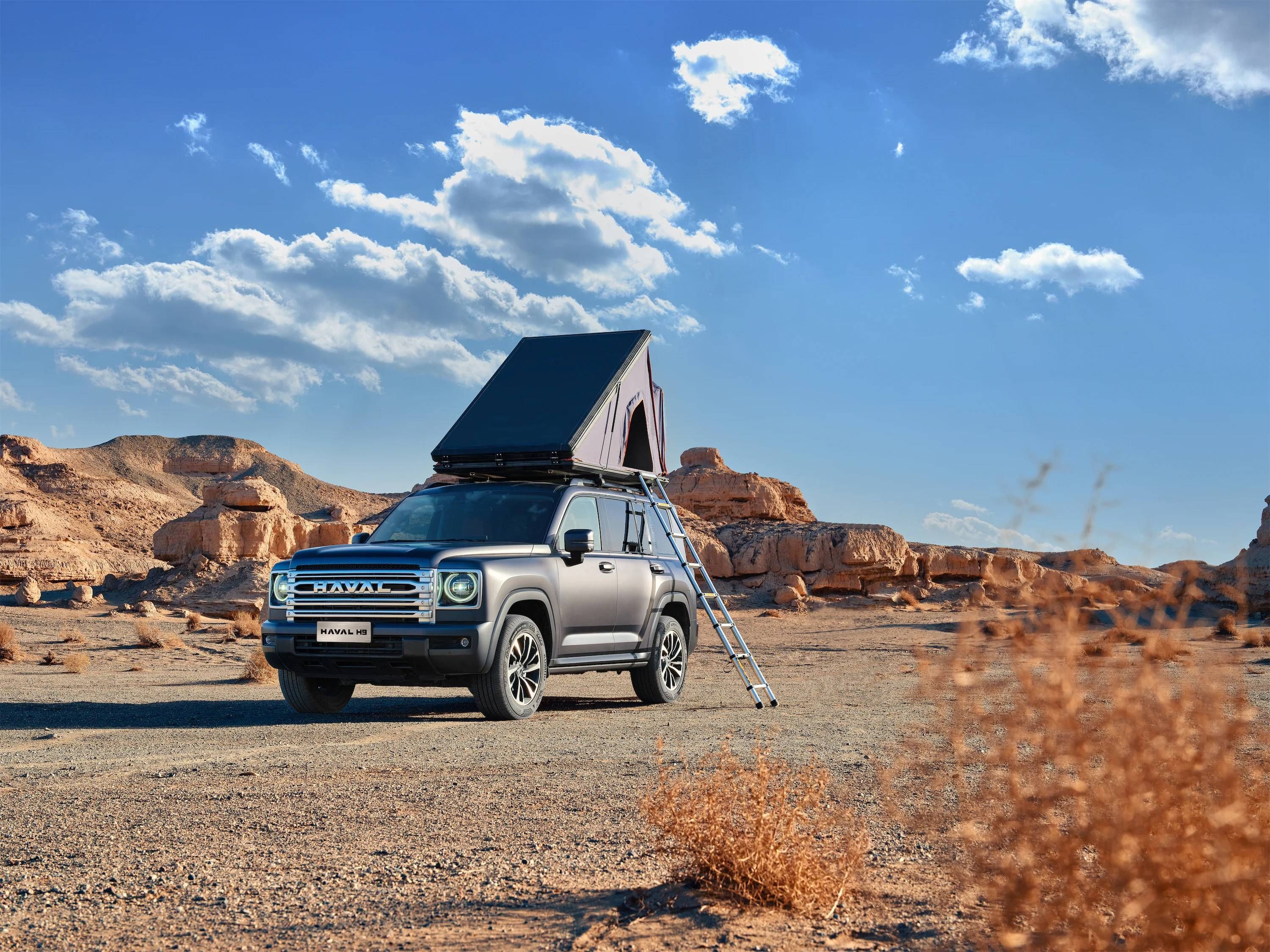 Haval H9 with rooftop tent set up in a desert landscape