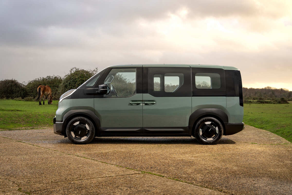 Side profile of the Kia PV5 Passenger parked outdoors, showing its upright shape, sliding doors and spacious body design.
