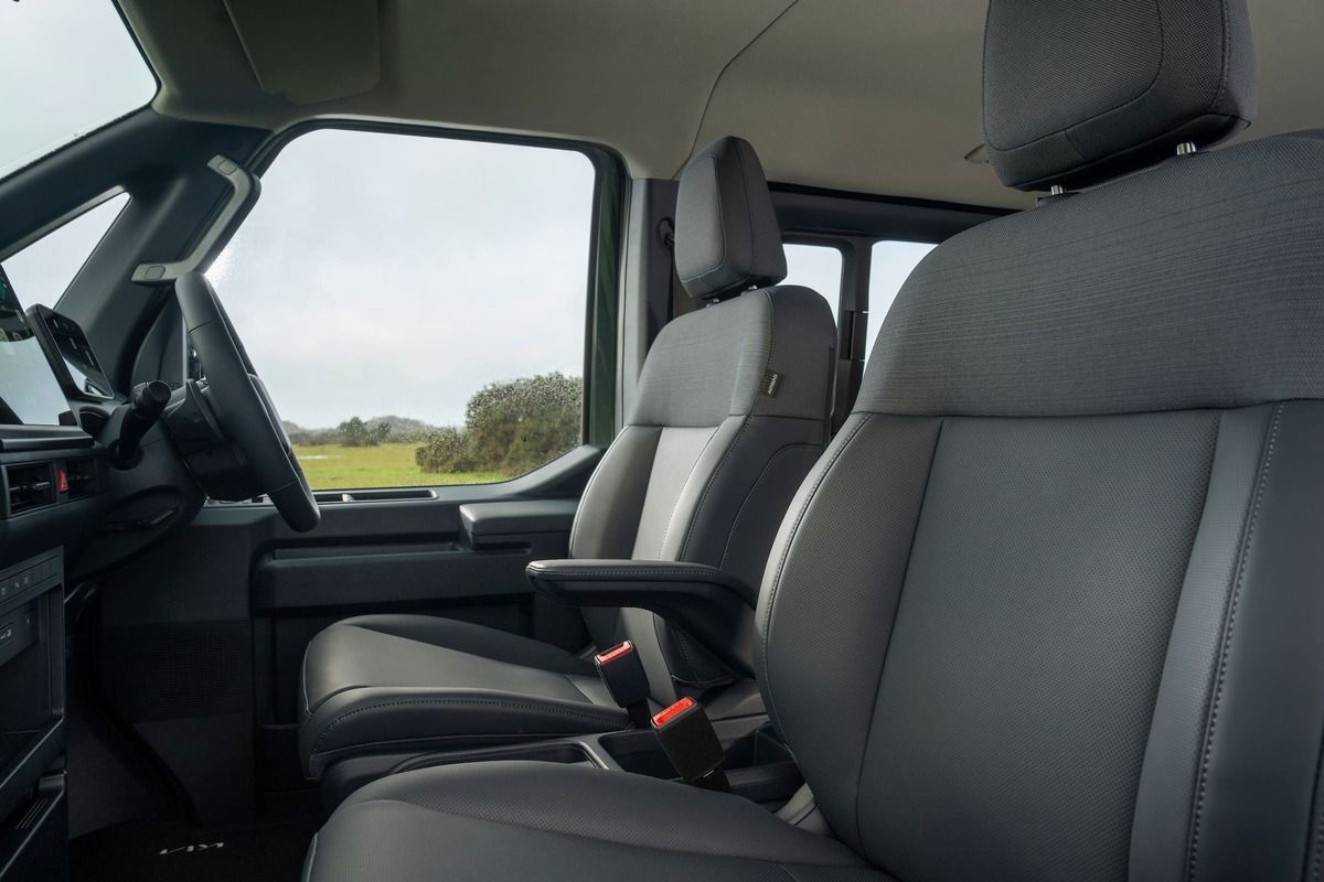 Front seats of the Kia PV5 featuring durable upholstery, armrests, and a driver-focused cabin layout.