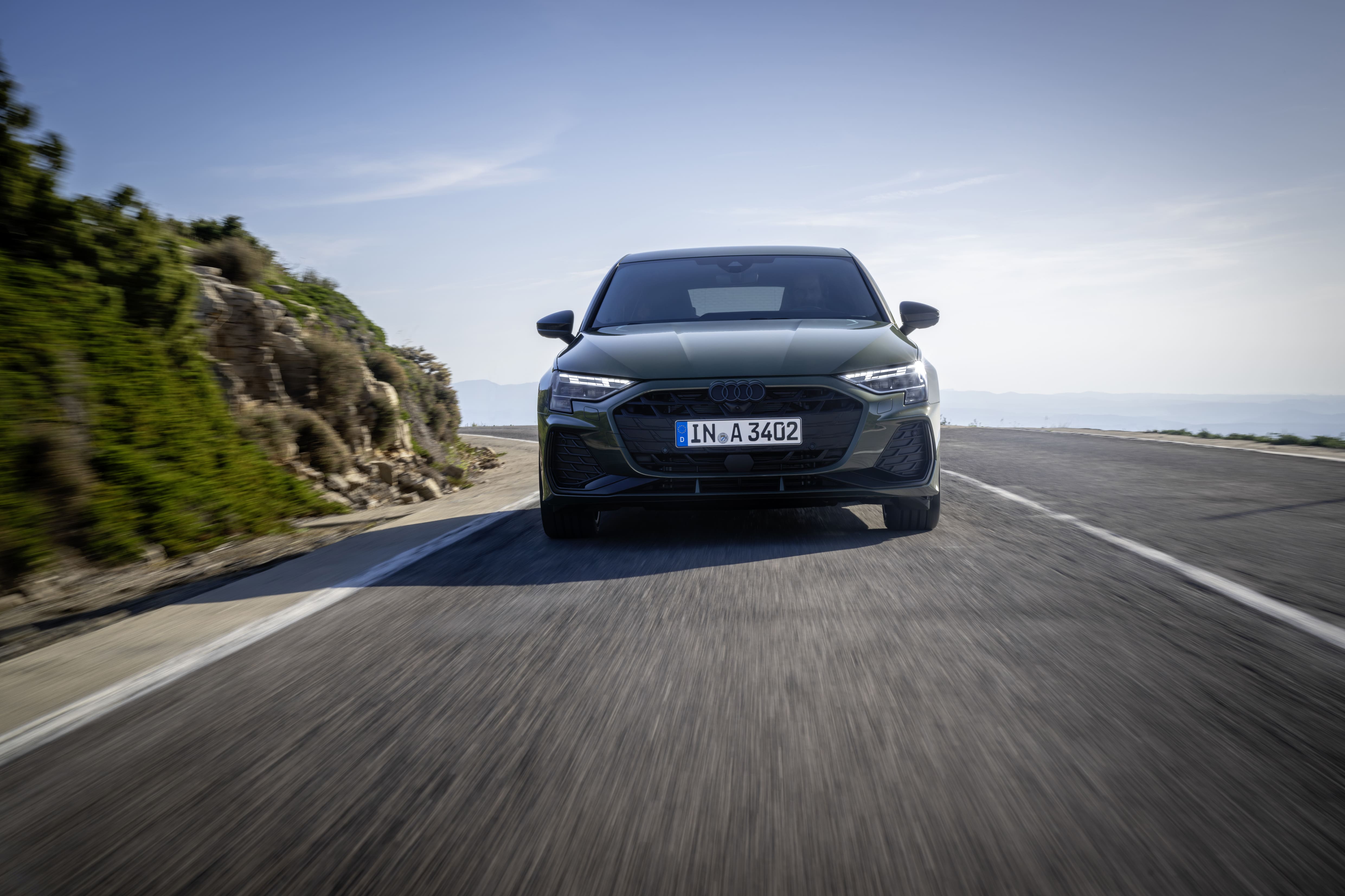 Front view of the 2026 Audi A3 Sportback driving on a winding mountain road with updated LED daytime running lights.