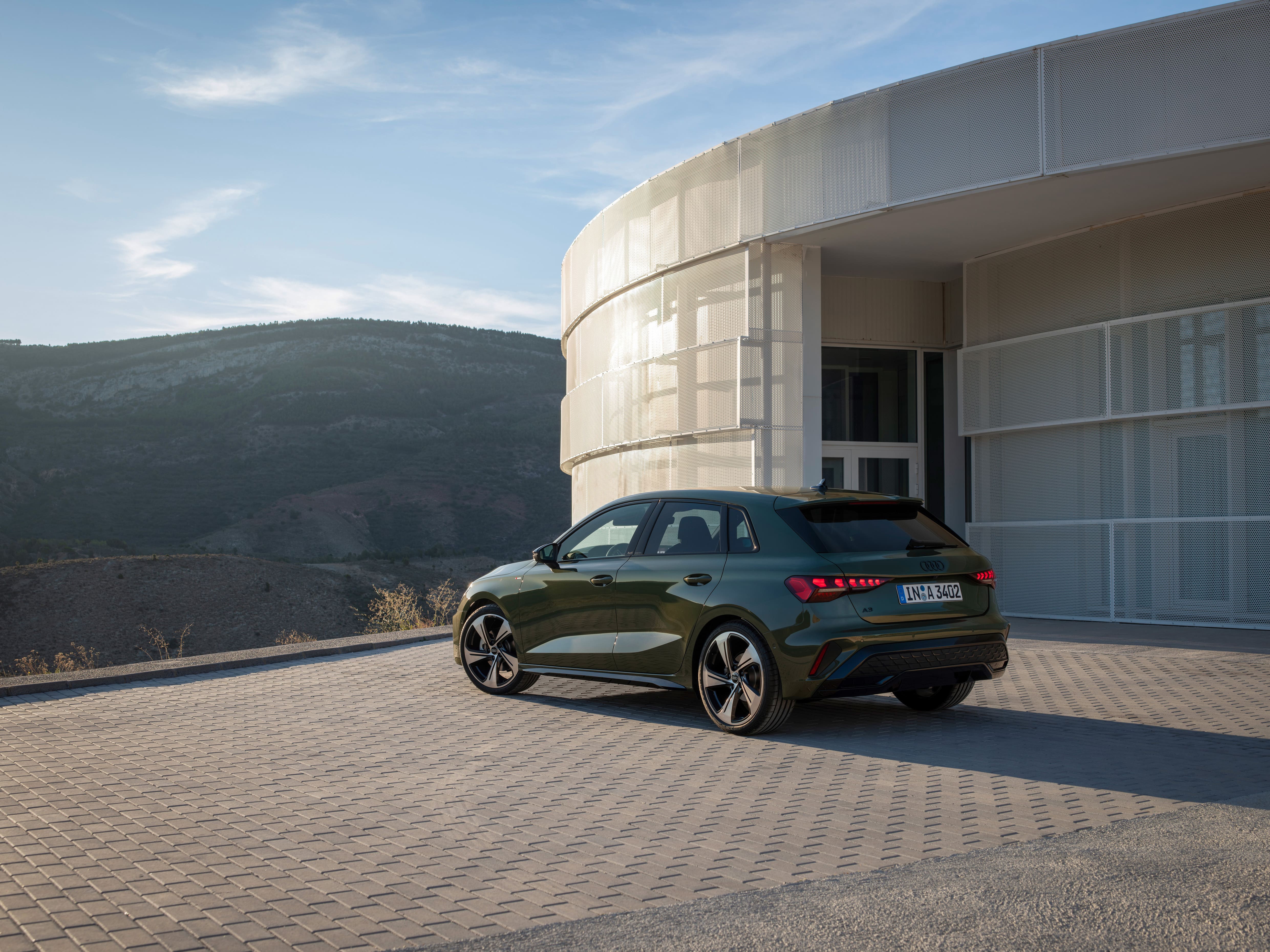 Rear three-quarter view of the 2026 Audi A3 Sportback parked outside a modern building.