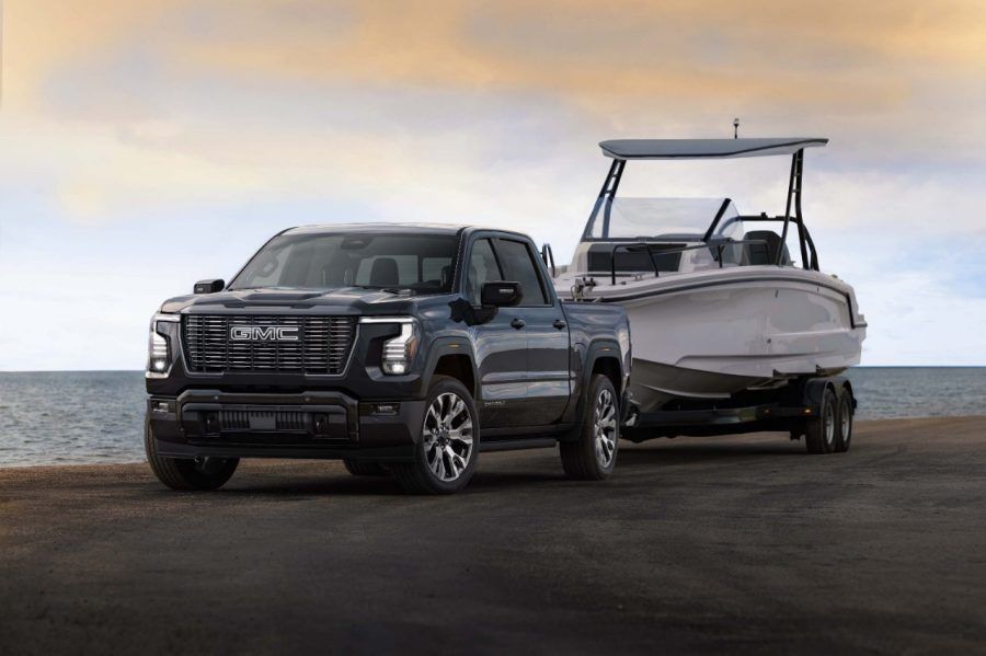 The 2027 GMC Sierra Denali Ultimate towing a large boat, showcasing its towing capability and V8 performance.