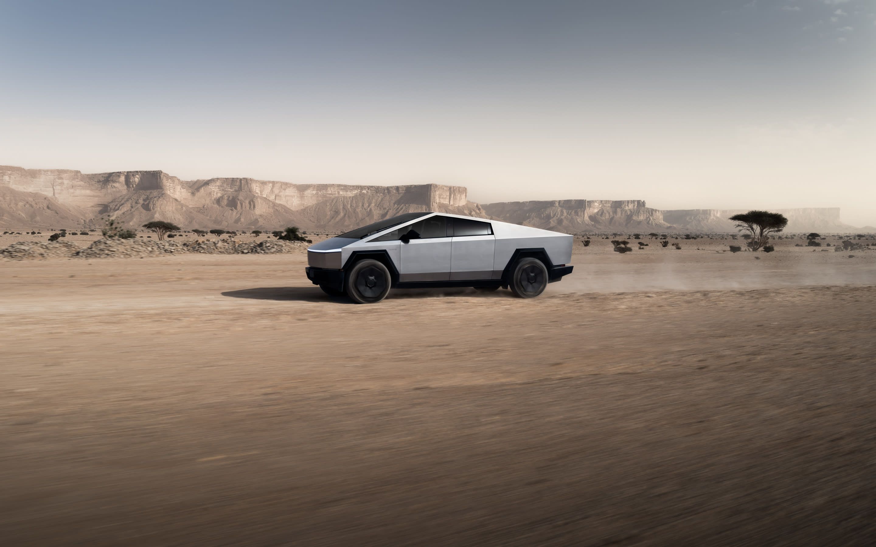 Tesla Cybertruck driving across a desert landscape, highlighting its futuristic design