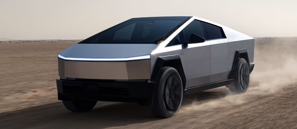 Tesla Cybertruck driving across desert terrain, showcasing its futuristic stainless steel exterior design.