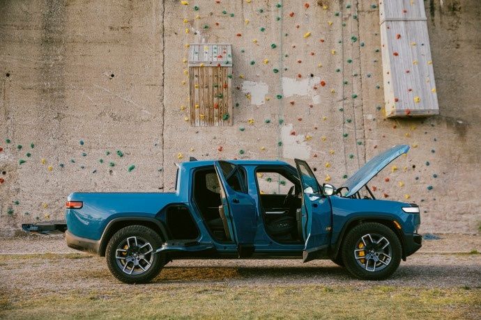Rivian R1T electric pickup with open doors and front trunk showcasing practical utility features
