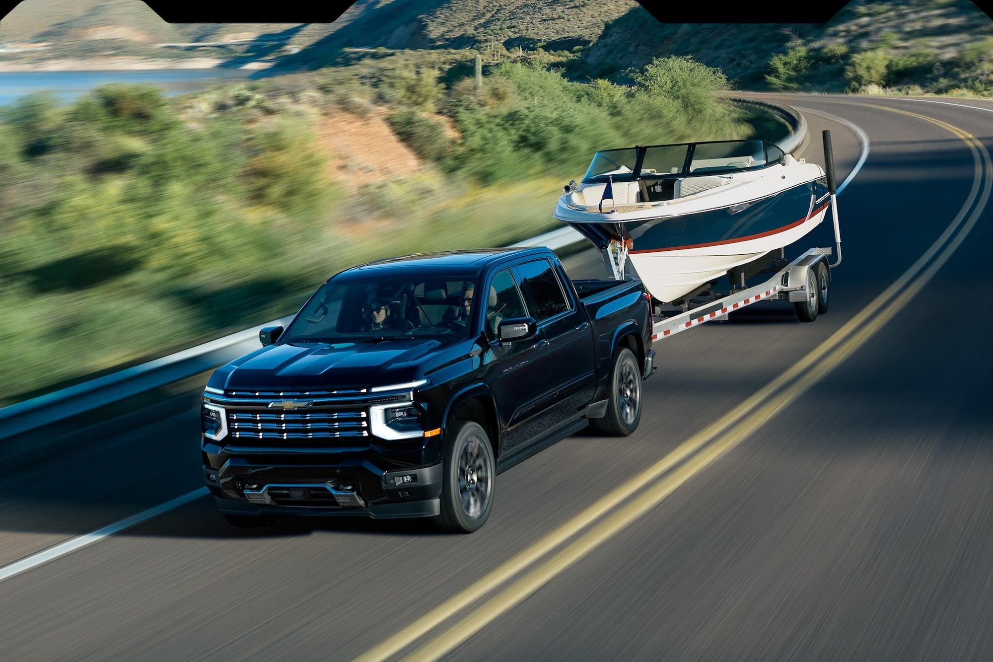 2027 Chevrolet Silverado 1500 towing a boat on a scenic highway