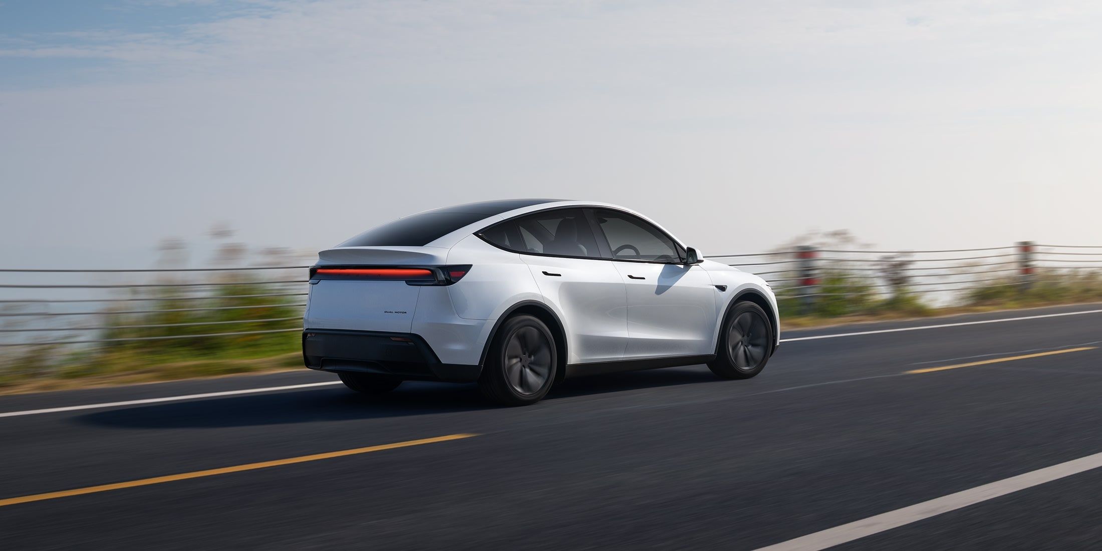 Tesla Model Y rear three-quarter view driving on an open highway